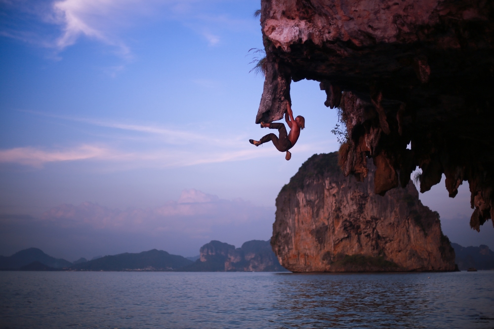 male climber deep water solos a limestone cliff in Krabi, Thailand
