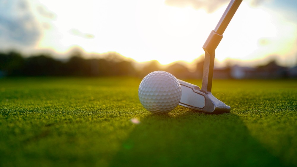 A golf ball and club on a golf course A golf ball and club on a golf course